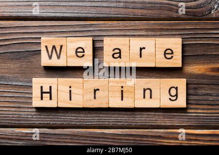 Stiamo assumendo parole scritte su blocco di legno. Stiamo affittando il testo sul tavolo di legno per il vostro desing, concetto della vista superiore. Foto Stock
