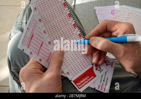 Primo piano della persona che sceglie di giocare d'azzardo Holding compilando i moduli di scontrino della lotteria National lotto Form England UK UK GB Great Britain Foto Stock