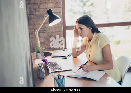 Primo piano ritratto di giovane ragazza latina concentrata guardando il computer portatile e prendere appunti al suo diario in un moderno bel posto di lavoro Foto Stock