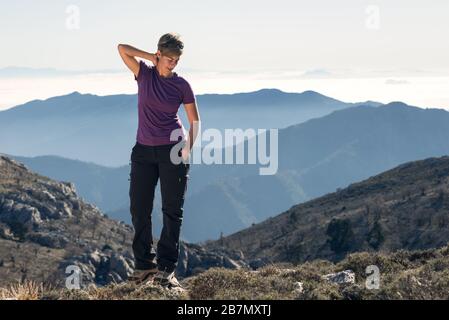 Donna escursionista che fa stretching sulla cima della montagna. Foto Stock