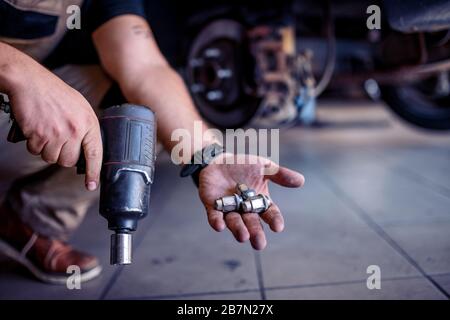 Il meccanico dell'auto tiene le viti in mano, primo piano. Foto Stock