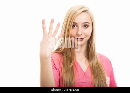 Ritratto di giovane infermiera femminile con scrub che mostra il numero quattro isolato su sfondo bianco con spazio di copia pubblicità area Foto Stock
