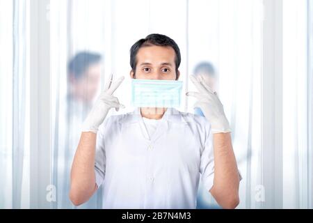 Medico asiatico uomo in guanti protettivi che indossano influenza. Prevenire la malattia influenzale Coronavirus Foto Stock