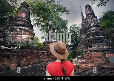 Donna in hat guardando antichi stupa in rovina in Ayutthaya, Thailandia Foto Stock