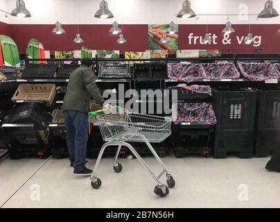 Scaffali quasi vuoti dove frutta e verdura sono di solito stoccati nel Sainsbury's a Clapham Junction, Londra, il giorno dopo che il primo ministro Boris Johnson ha invitato le persone a stare lontano da pub, club e teatri, lavorare da casa se possibile ed evitare tutti i contatti non essenziali e viaggiare per ridurre l'impatto della pandemia di coronavirus. Foto Stock