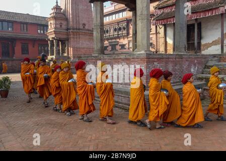 Bhaktapur, Nepal - 28 gennaio 2020: Giovani monaci buddisti che camminano al mattino elemosine a Bhaktapur in Nepal Foto Stock