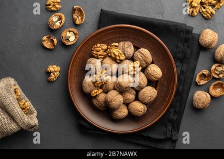 Dadi. Kernel di noce e noci intere su tavola di pietra scura. Vista dall'alto, disposizione piatta. Foto Stock