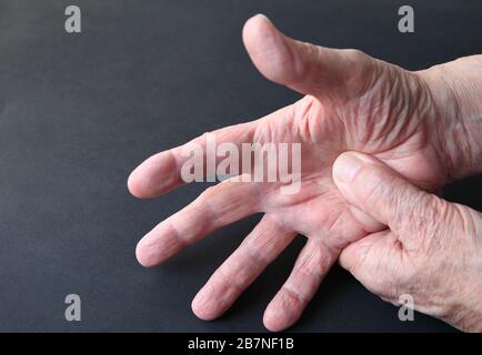 Un uomo preme un pollice nel palmo su uno sfondo scuro Foto Stock