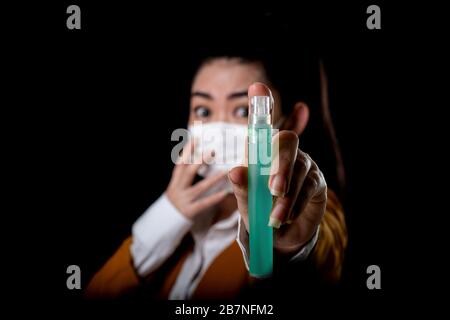 Donna d'affari di giovane Asia donna che mette su una maschera respiratore N95 con la mano che applicando spray di alcol dalla bottiglia di plastica o antibatterico Foto Stock