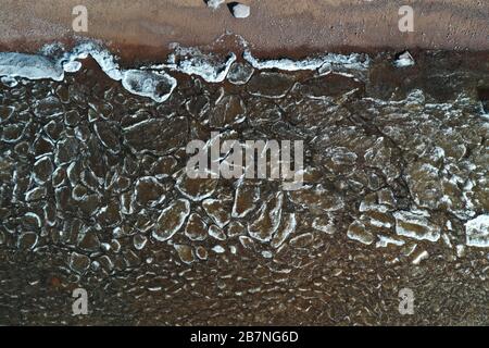 Pezzi di ghiaccio galleggiante sulle onde, placche di ghiaccio, costa sabbiosa, pietre, paesaggio primaverile, tempo soleggiato, pacificazione Foto Stock