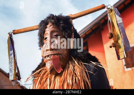 Ritratto di una persona non identificata che indossa una maschera pagana alla sfilata di carnevale Pust. Demone che cammina per strada. Foto Stock