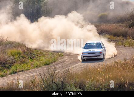 Estate strada sterrata asciutta. Giorno di sole. Auto da rally e molta polvere in una curva brusca Foto Stock