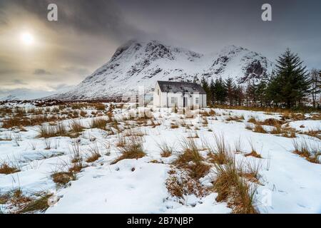 Un vecchio cottage di montagna sotto una coperta di neve a Glencoe nelle Highlands scozzesi Foto Stock