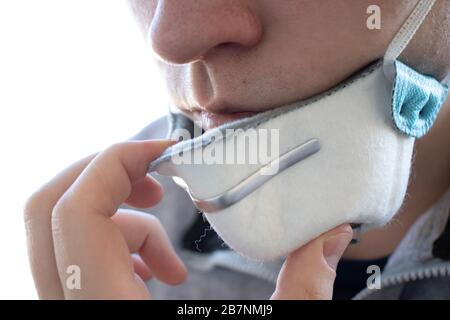 Uomo faccia da vicino. La persona toglie o mette su una maschera medica o respiratore Foto Stock