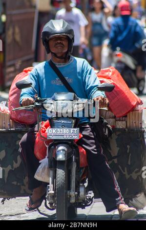 L'uomo su una motocicletta trasporta molte borse. Bali, Indonesia Foto Stock