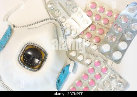 Concetto di medicina sanitaria. Respiratore o maschera medica con vista dall'alto di protezione. Piatto con pillole di droga su sfondo bianco Foto Stock