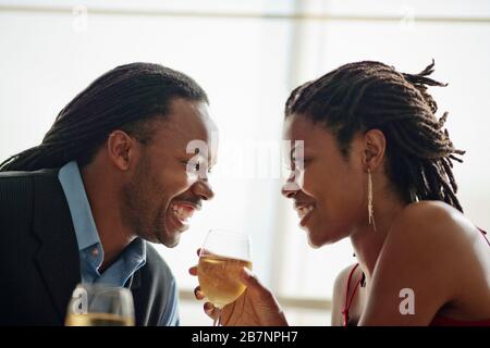 Una giovane coppia felice che guarda gli occhi l'un l'altro mentre si gode una cena romantica. Foto Stock