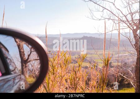 Primo piano dello specchietto per auto. Orizzonte, montagne, foresta, cielo, natura. Riflessione nello specchio. Viaggi e turismo in auto. Spazio di copia. Foto Stock