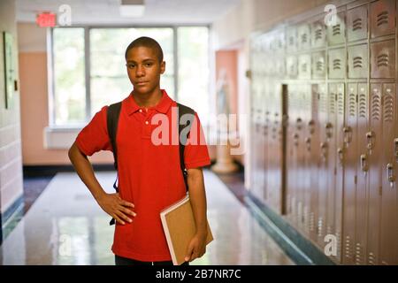 Ragazzo adolescente in piedi nel corridoio della scuola Foto Stock