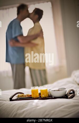 Colazione seduta su un letto mentre un bacio di coppia. Foto Stock