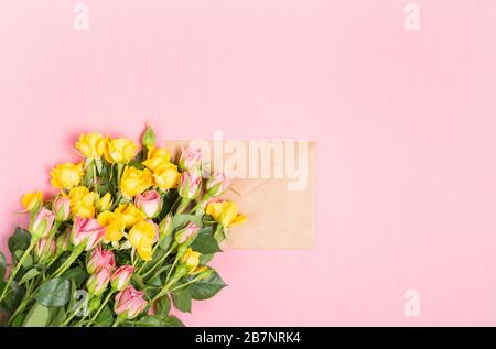 Busta vuota con posto per il testo del biglietto di auguri di primavera. rose su sfondo rosa. Disposizione piatta, vista dall'alto Foto Stock