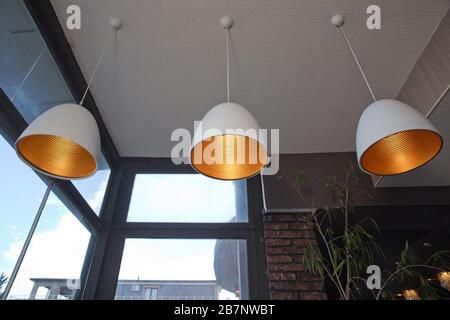 Plafoniera di stile retrò appesa al soffitto di un moderno ristorante industriale. Primo piano lampada incandescente, luce gialla della lampada appesa Foto Stock