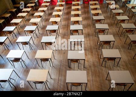 file di sedie e tavoli vuoti nella sala esami della scuola superiore Foto Stock