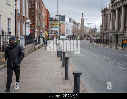 Dublino, Irlanda. 17 Marzo 2020. 17 marzo 2020. Festival/parata di St. Patricks a Dublino. O'Connell Street, il centro della città di Dublino, normalmente pieno di visitatori per una delle più grandi celebrazioni culturali del mondo è quasi deserta a causa del Corona Virus / Covid 19. Nella foto è raffigurato un uomo con il viso coperto da una sciarpa. Credit: Barry Cronin/Alamy Live News Foto Stock