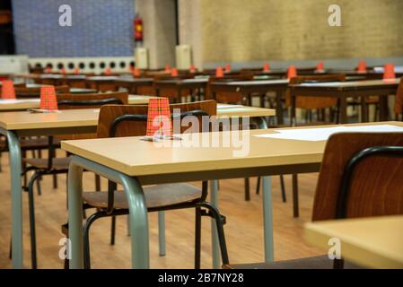 file di sedie e tavoli vuoti nella sala esami della scuola superiore Foto Stock