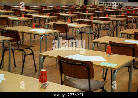 file di sedie e tavoli vuoti nella sala esami della scuola superiore Foto Stock