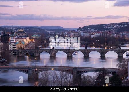 Il paesaggio urbano di Praga al crepuscolo. Classica vista panoramica dei ponti sul fiume Moldava Foto Stock