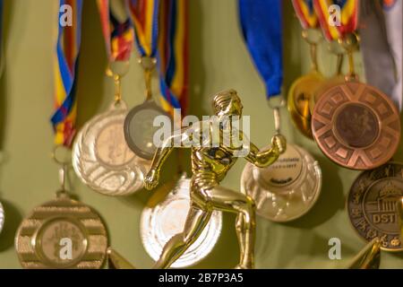 Un trofeo d'oro che simboleggia un atleta in corsa e molte medaglie sullo sfondo, Bucarest, Romania Foto Stock