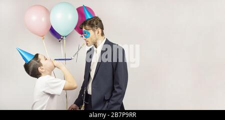 Due ragazzi che si posano con gioia durante il loro compleanno. Due ragazzi con palloncini. Sorridono. Cono di cappello, bicchieri, fischi. Banner. Posizionare per il testo Foto Stock