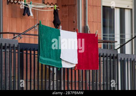 Tre asciugamani verdi, bianchi, rossi disposti come bandiere italiane appesi da un balcone in Italia durante il blocco nazionale Coronavirus(COVID-19) Foto Stock