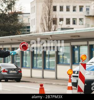 Kehl, Germania - 16 marzo 2020: Un ufficiale tiene FERMA segnale di stop al valico di frontiera a Kehl dalla Francia Strasburgo durante le misure di crisi nella lotta contro il romanzo coronavirus Foto Stock