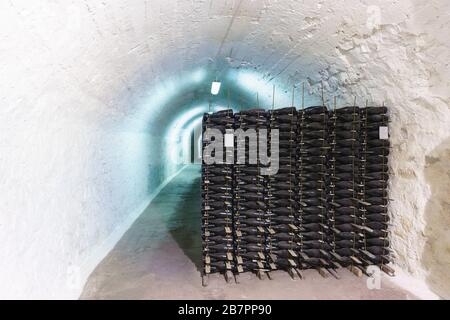 Pile di bottiglie nei tunnel delle cantine della fabbrica di spumante. Esposizione a lungo termine a basse temperature Foto Stock