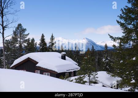 Cabina montagna inverno tempo Gol, Norvegia, con montagne innevate in Hemsedal sullo sfondo. Foto Stock