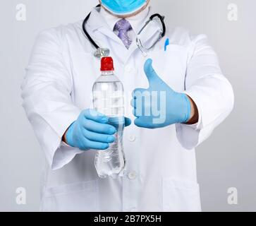 medico in un cappotto bianco e guanti in lattice blu contiene una bottiglia trasparente di acqua, è necessario consumare più acqua per sentirsi meglio Foto Stock