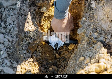 Garden worker che installano nel sistema di irrigazione a gocciolamento di tubi sotterranei posa di sprinkler Foto Stock