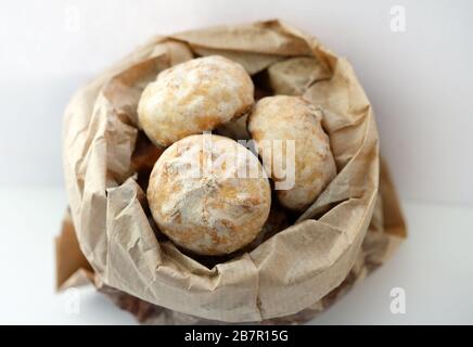 Biscotti in un sacchetto di carta su sfondo bianco. Torte farcite di pan di zenzero ricoperte di glassa di zucchero. Foto Stock