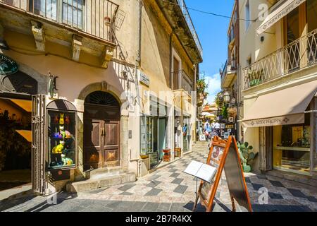 Una strada colorata di negozi e caffè nella città di Taormina sull'isola di Sicilia. Foto Stock