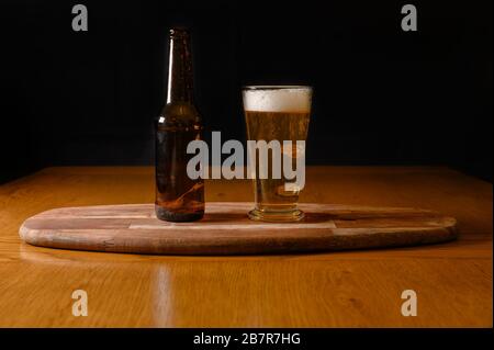 Birra fresca isolata su tavolo di legno con bottiglia Foto Stock