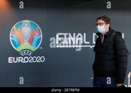 (200318) -- BUCAREST, 18 marzo 2020 (Xinhua) -- UN uomo che indossa una maschera passa da un logo del Campionato europeo DI Calcio EURO 2020 esposto su un muro all'Aeroporto Internazionale Henri Coanda di Bucarest, Romania, 17 marzo 2020. L'organo di governo del calcio europeo UEFA ha deciso di rinviare il Campionato europeo di quest'estate al 2021 a causa dell'epidemia di coronavirus. Il presidente rumeno Klaus Iohannis ha annunciato che il paese entrerà in uno stato di emergenza a partire dal marzo 16, nel tentativo di garantire che il governo utilizzi tutte le risorse per combattere l'epidemia COVID-19. (Foto di Cris Foto Stock