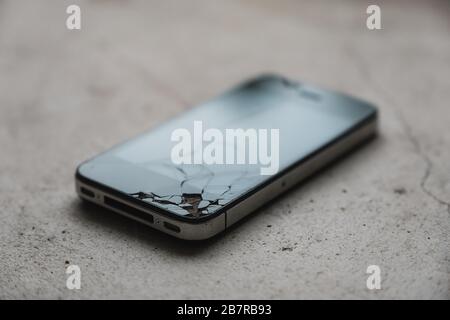 Un telefono cellulare incrinato sul pavimento Foto Stock