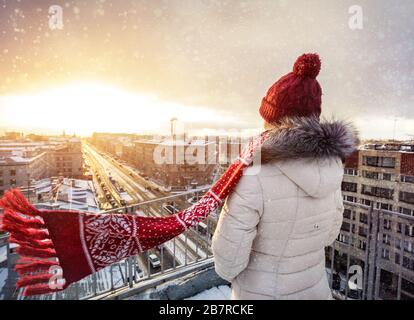 La donna nel cappello di Natale e sciarpa rossa sul tetto presso la caduta di neve a San Pietroburgo, Russia Foto Stock