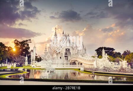 Wat Rong Khun il tempio bianco e uno stagno al tramonto spettacolare sfondo in Chiang Rai, Thailandia. Foto Stock