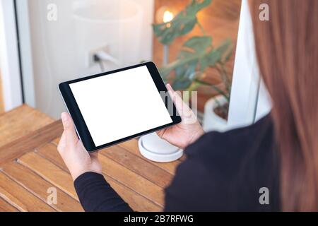 Immagine mockup di una donna che tiene e guarda un tablet pc nero con schermo bianco vuoto Foto Stock
