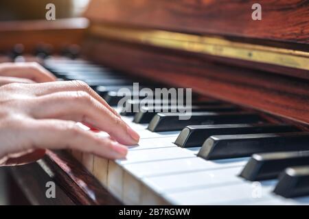 Immagine closeup delle mani che suonano un grande pianoforte in legno d'epoca Foto Stock