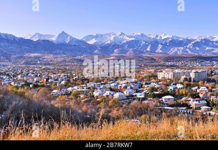 Parte alta della città di Almaty sullo sfondo delle montagne nella stagione autunnale; prima neve sui tetti delle case in autunno d'oro, bellezza e grandezza di K Foto Stock