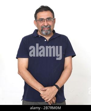 Un uomo indiano sorridente con un portiere in uno studio su sfondo bianco. Indossare occhiali e guardare la fotocamera. Foto Stock